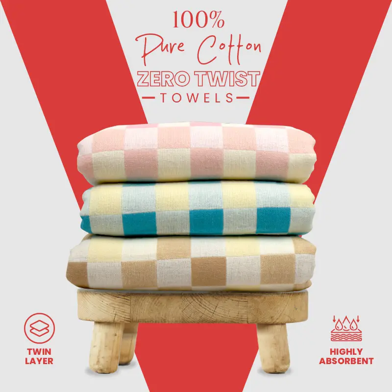 Three colors of ZAHYA zero twist towels stacked on a wooden stool against red and white background