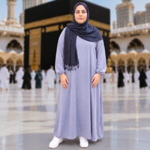 Woman wearing Zahya grey georgette Women's Ihram XXL with elastic cuffs and navy hijab, standing in front of the Kaaba, for Hajj and Umrah