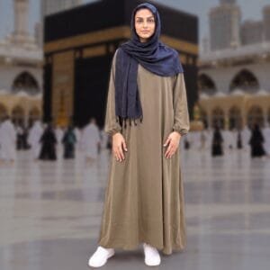 Woman wearing Zahya olive brown georgette Women's Ihram with elastic cuffs and navy hijab, standing in front of the Kaaba, for Hajj and Umrah